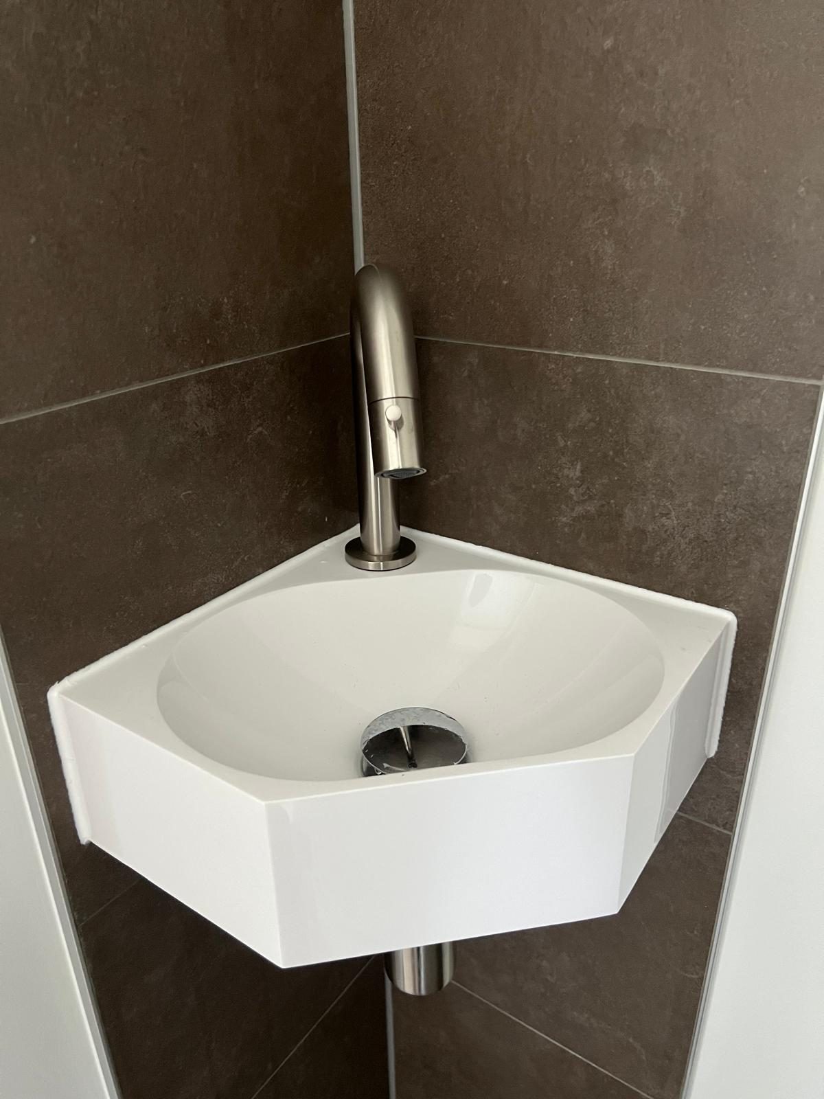 Compacte hoekwastafel in een gerenoveerde badkamer