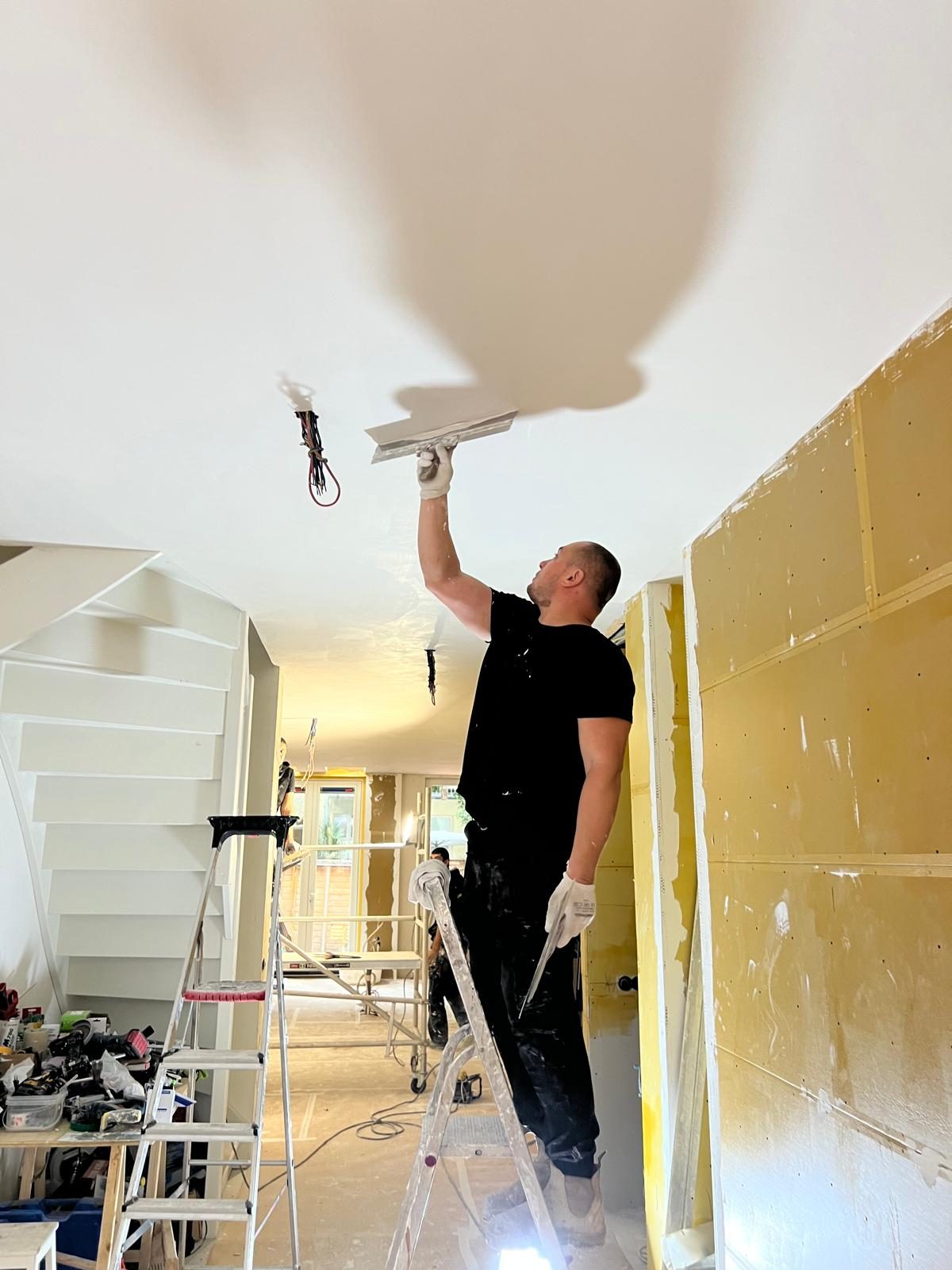 Stucadoor strijkt een plafond glad