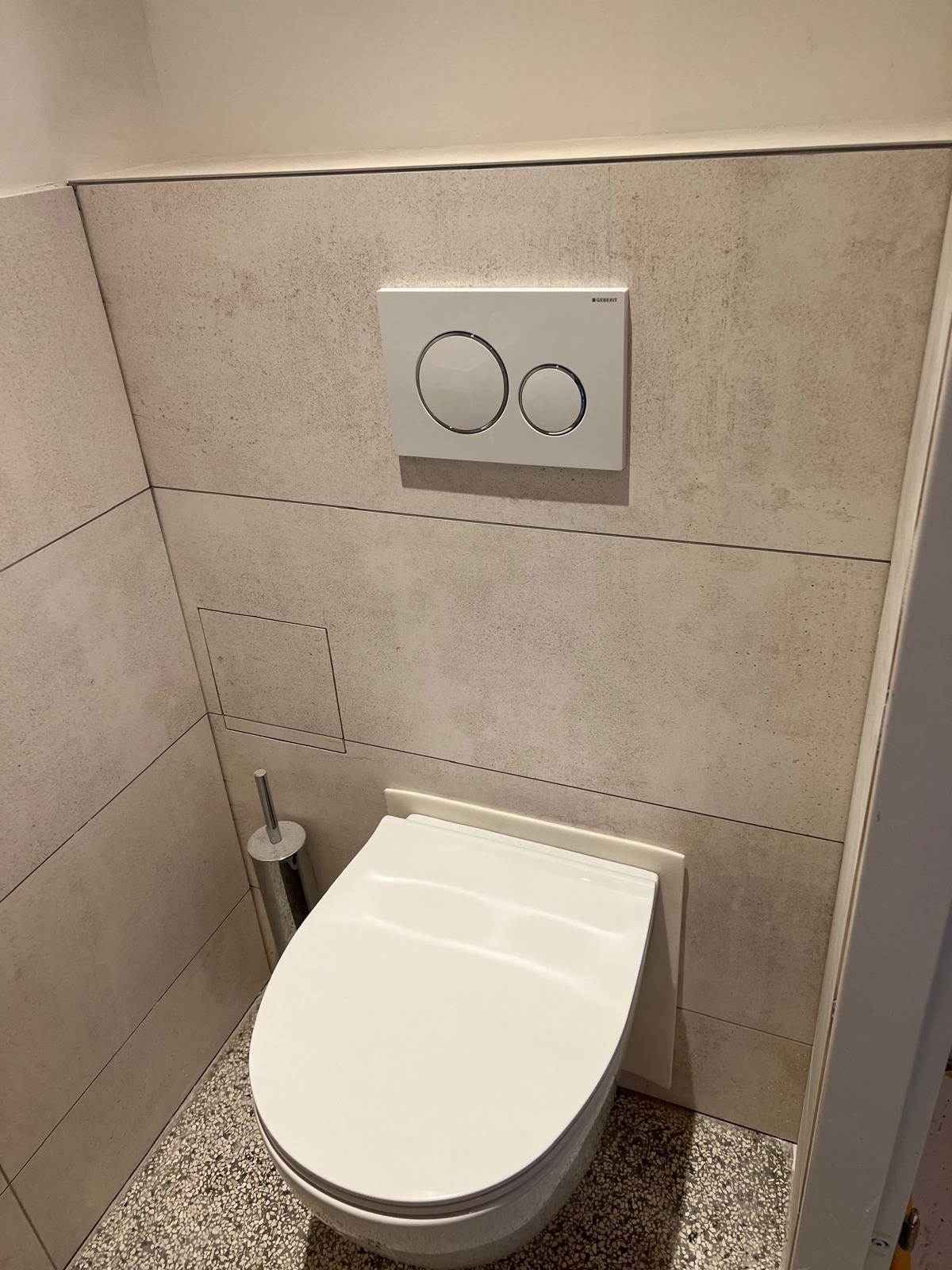 Hangend toilet met zandsteentegels en Geberit-bedieningsplaat