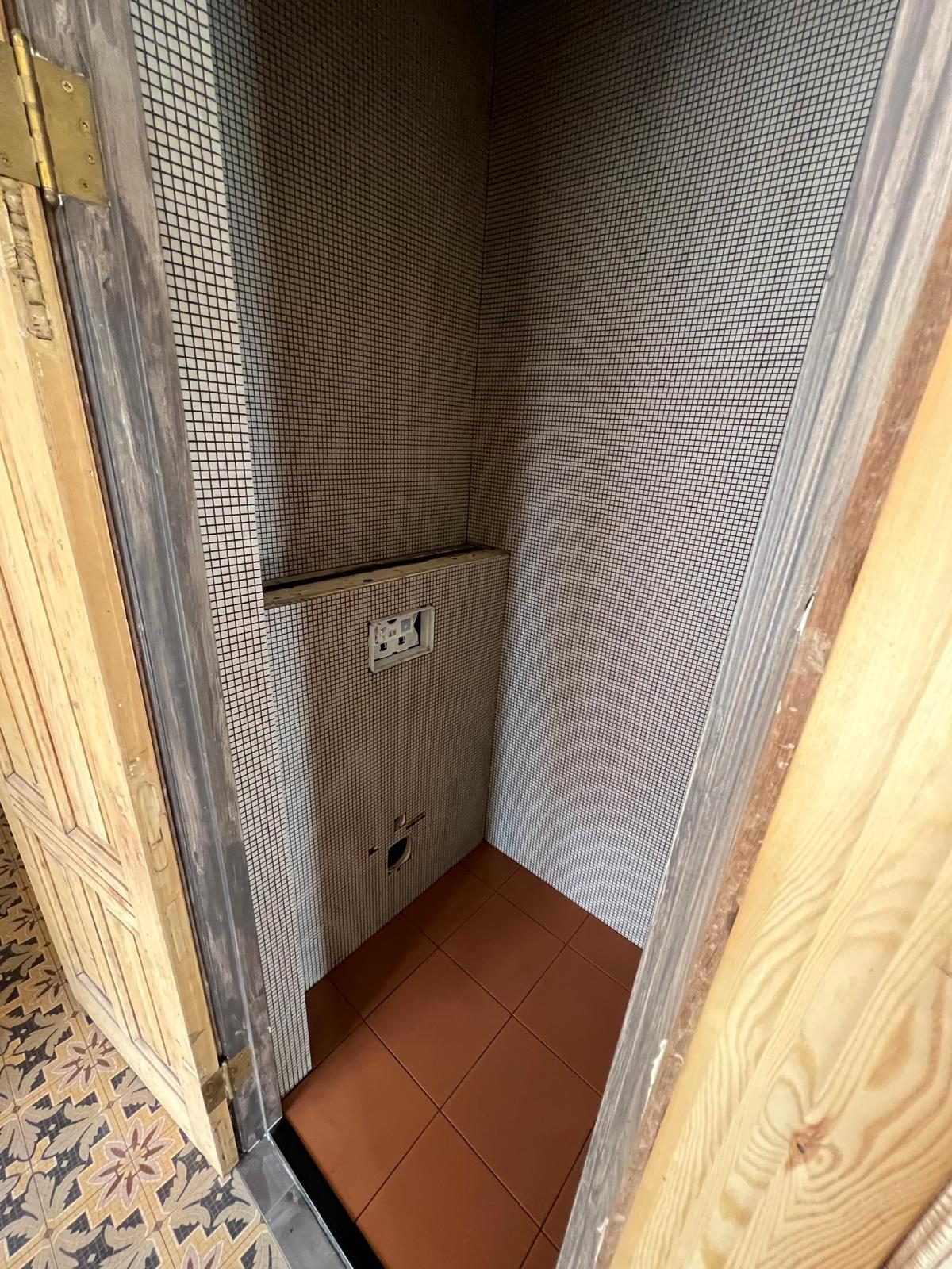 Oude toiletnis met mozaïektegels vóór de renovatie